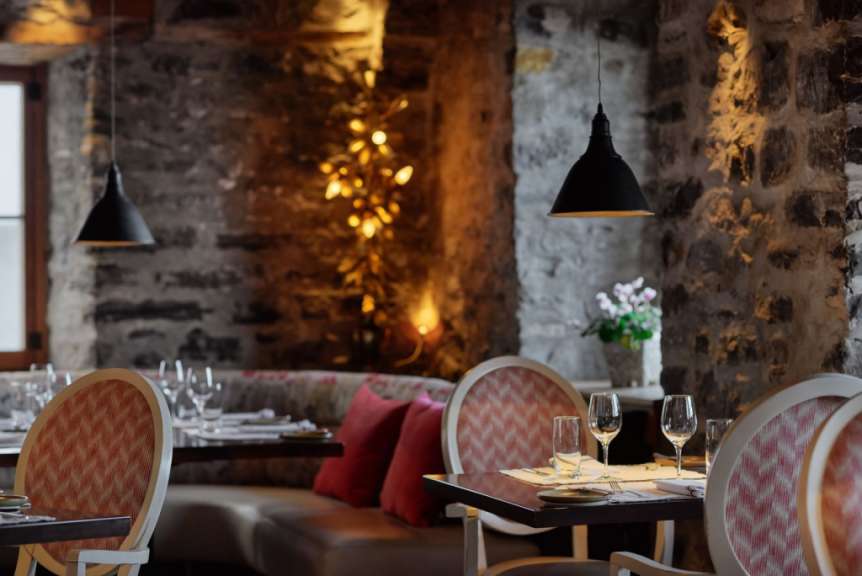 Ein Restaurant mit Tisch und Stühlen und einer Steinmauer
