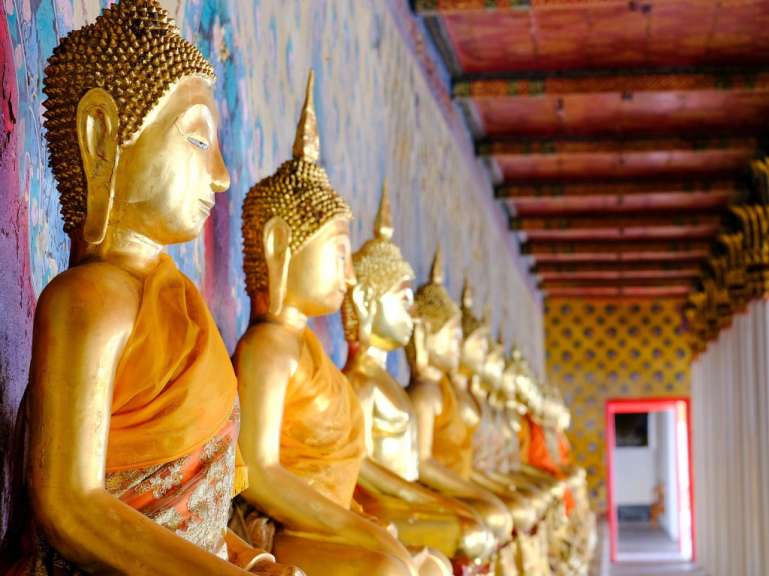 Eine Reihe von goldenen buddhistischen Statuen in einem Tempel