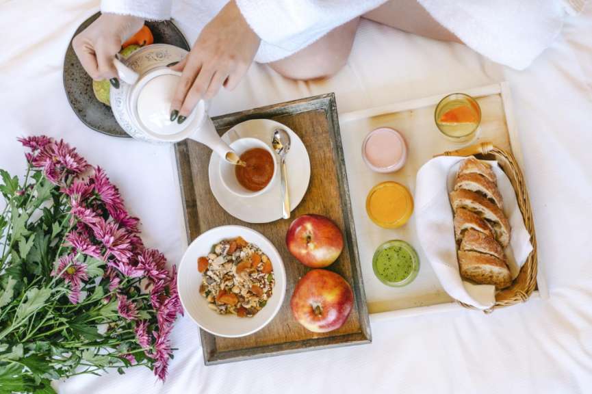 Eine Frau sitzt auf einem Bett mit einem Tablett voller Essen
