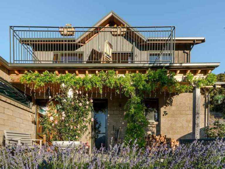 Die Vorderseite eines Hauses mit einem Balkon und Lavendel im Vordergrund .