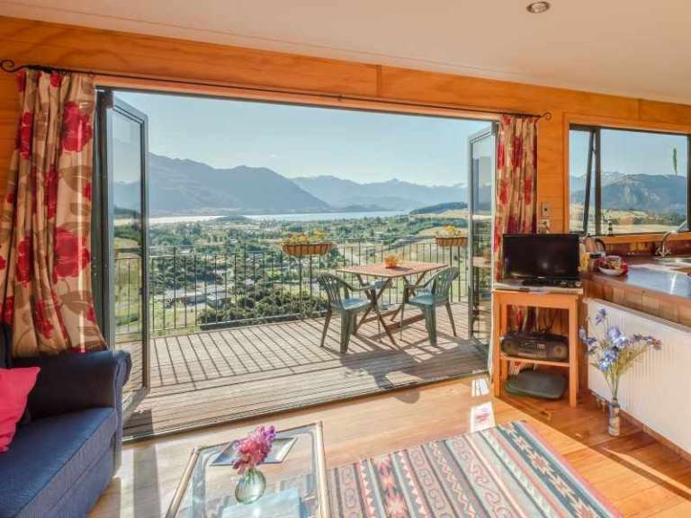 Ein Wohnzimmer mit Blick auf einen Balkon mit Tisch und Stühlen
