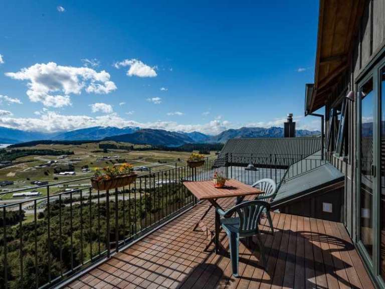 Ein Balkon mit einem Tisch und Stühlen und einem Blick auf die Berge .