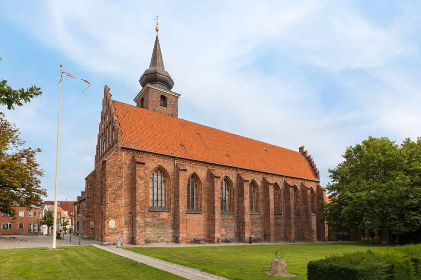 Eine rote Backsteinkirche mit einem goldenen Kreuz auf dem Turm