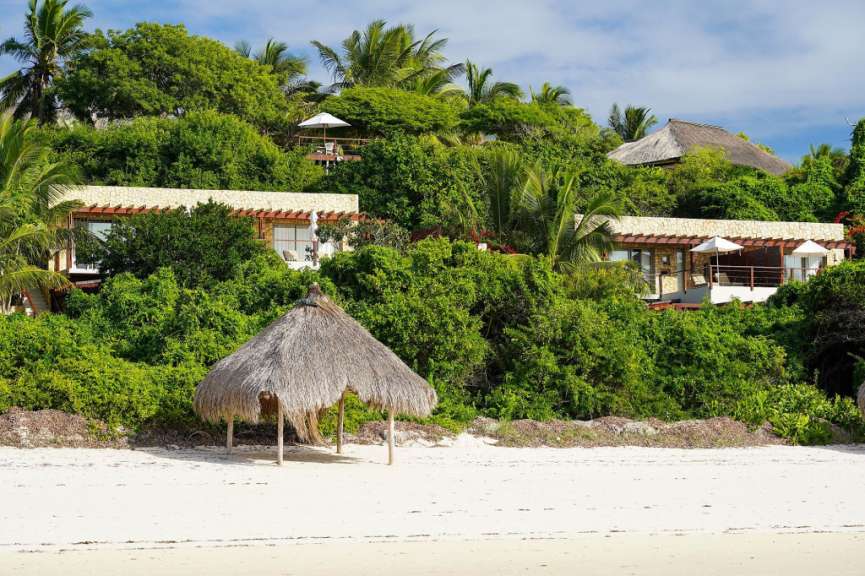Ein kleines Strohdach am Strand vor einem großen Gebäude