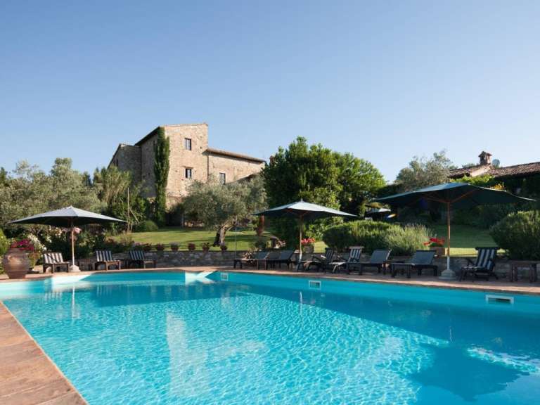Ein großer Swimmingpool mit Liegestühlen und Sonnenschirmen umgeben