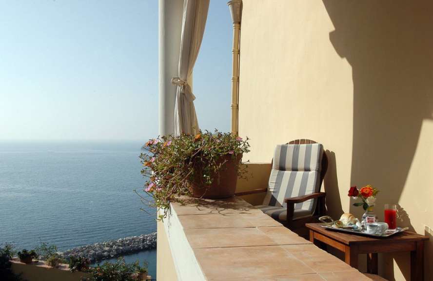 Ein Stuhl sitzt auf einem Balkon mit Blick auf das Meer