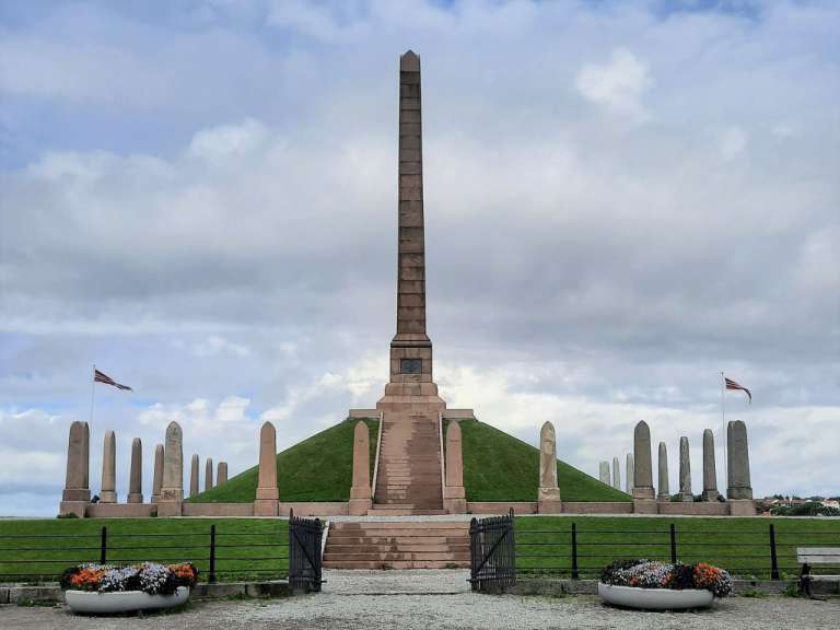 Ein großer Obelisk steht auf einem grünen Hügel