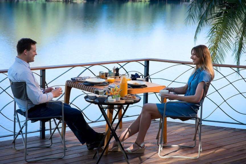 Ein Mann und eine Frau sitzen an einem Tisch auf einem Deck mit Blick auf einen See