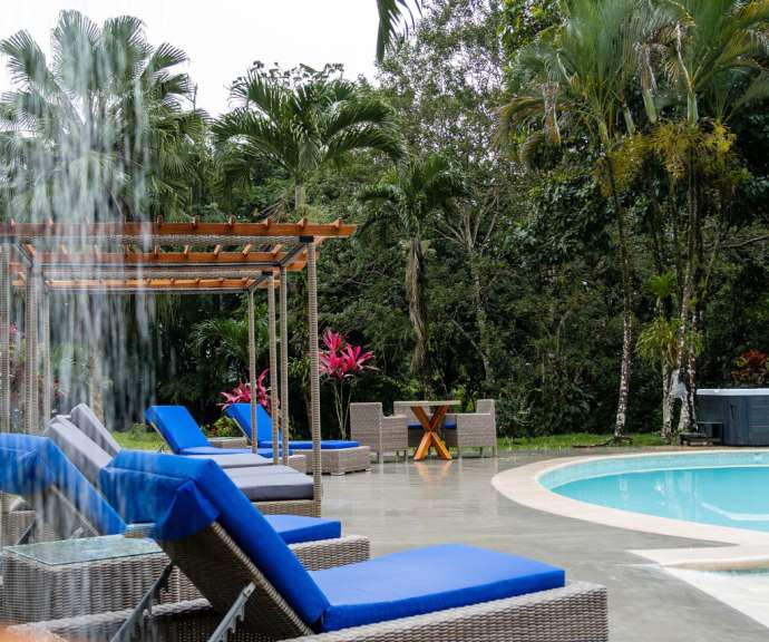 Liegestühle neben einem Pool mit einem Wasserfall im Hintergrund