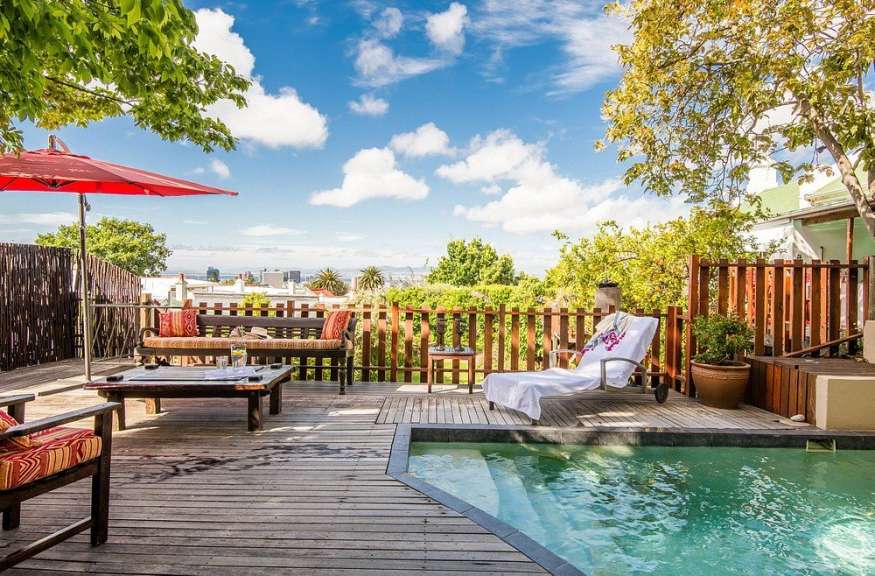 Ein Holzdeck mit einem Swimmingpool und einem roten Regenschirm