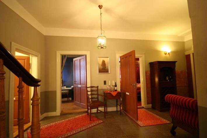 Ein Flur mit mehreren Türen, ein Treppengeländer, ein kleiner Tisch mit Stuhl, ein Schrank und ein gestreiftes Sofa.