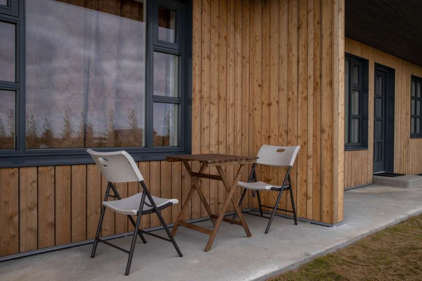 Ein Tisch und zwei Stühle vor einem Holzgebäude