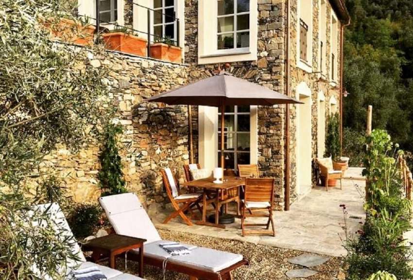 Eine Terrasse mit einem Tisch und Stühlen und einem Regenschirm vor einem Steingebäude