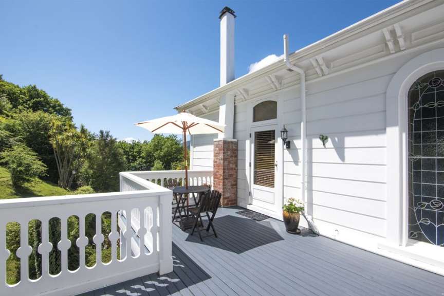 Ein weißes Haus mit einem Balkon mit Tisch und Stühlen