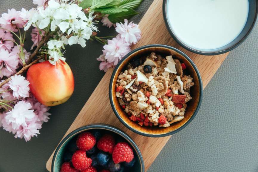 Drei Schüsseln mit Müsli und Früchten auf einem Holzbrett