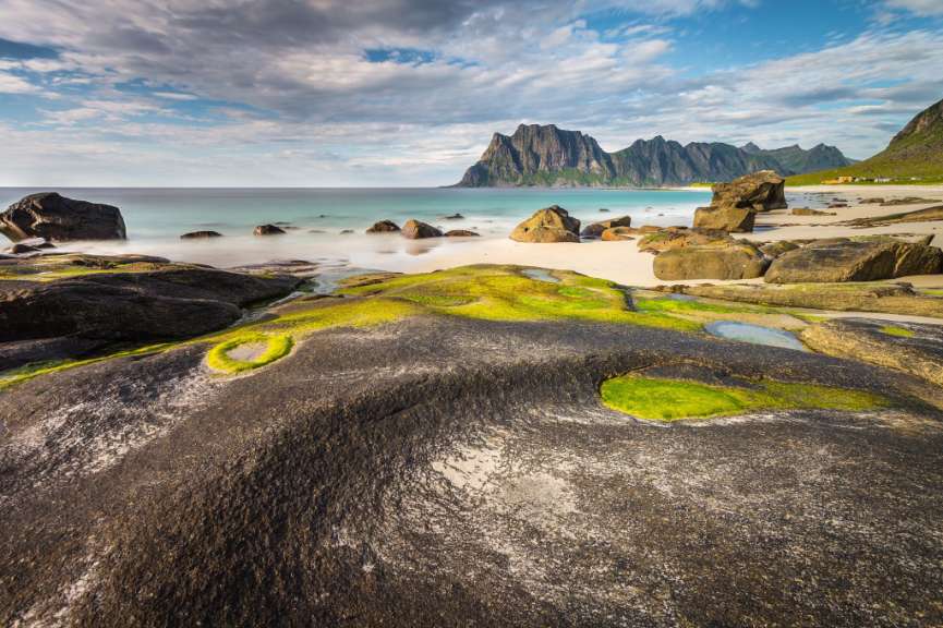 Ein felsiger Strand mit Bergen im Hintergrund