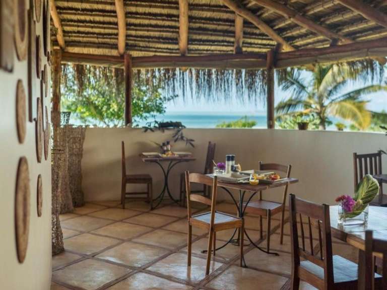 Tische und Stühle auf einer Terrasse mit Blick auf das Meer