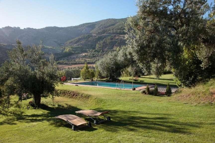 Ein großer Pool in einem grünen Feld mit Blick auf die Berge
