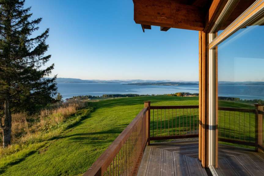 Ein Balkon mit Blick auf einen See und eine grüne Wiese