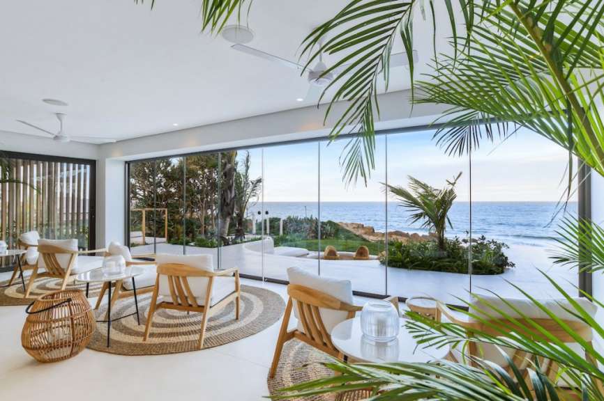 Ein Wohnzimmer mit einem Tisch und Stühlen mit Blick auf das Meer