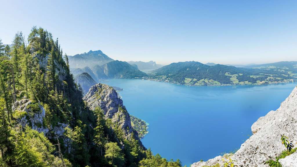 Ein Mann steht auf einem Felsen mit Blick auf einen See