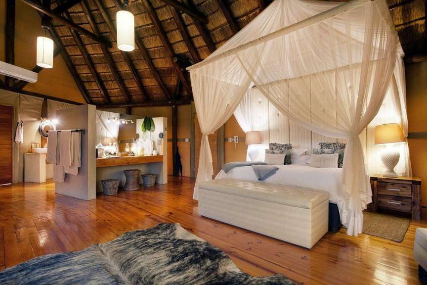 Ein luxuriöses Zimmer mit Himmelbett, rustikalen Holzmöbeln und einem Strohdach.