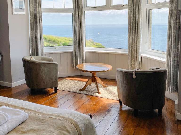 Ein Zimmer mit zwei Stühlen und einem Tisch mit Blick auf das Meer