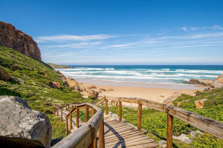 Eine Holztreppe führt hinunter zu einem Strand
