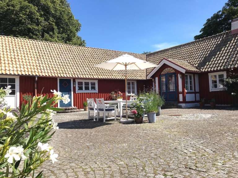 Ein weißer Regenschirm steht vor einem roten Haus