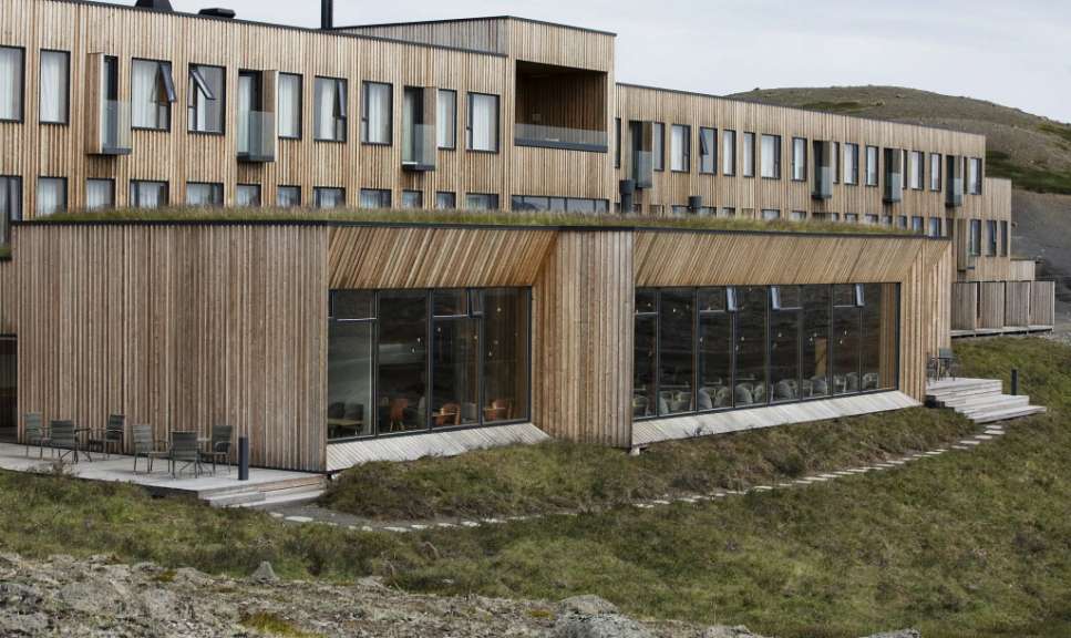 Ein Holzgebäude mit vielen Fenstern und einem grünen Dach