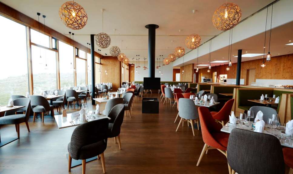 Ein Restaurant mit vielen Tischen und Stühlen und einem Kamin