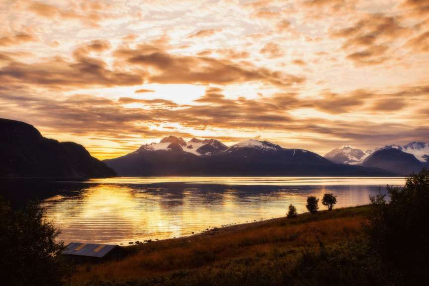 Sonnenuntergang über einem See mit Bergen im Hintergrund
