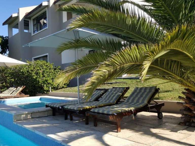 Liegestühle neben einem Swimmingpool mit einem Haus im Hintergrund