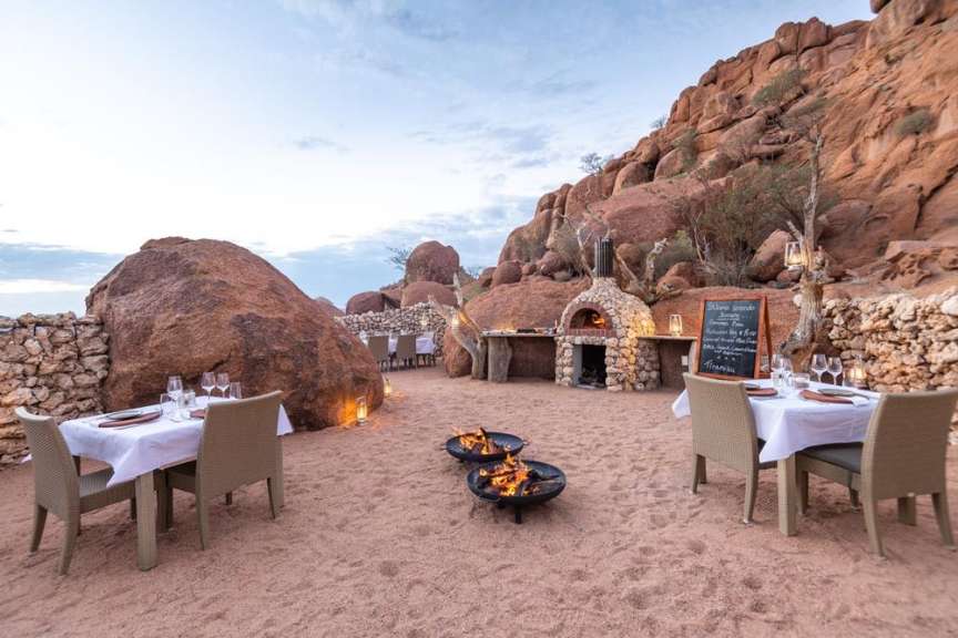Ein Tisch und Stühle im Sand neben einem Steinofen