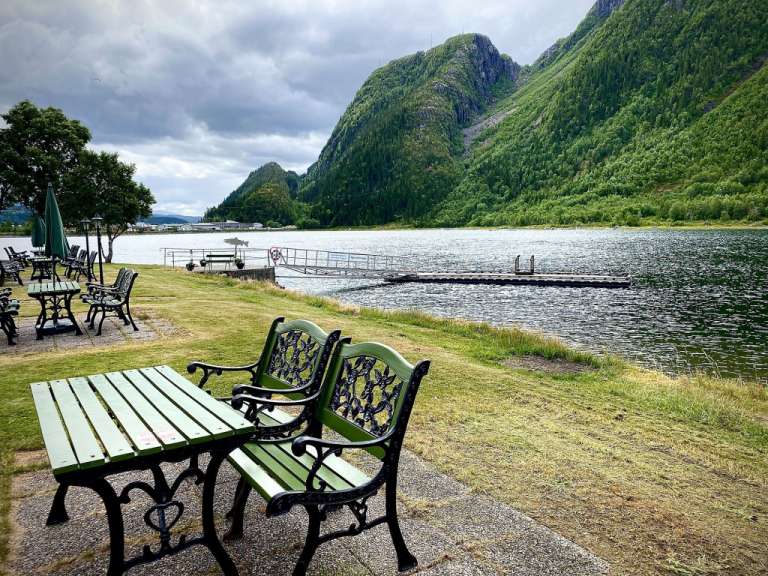 Ein Tisch und Stühle am Ufer eines Sees mit Bergen im Hintergrund