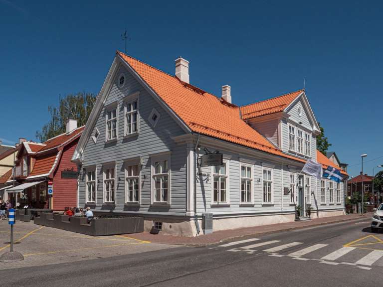 Ein großes weißes Holzhaus mit einem orangefarbenen Dach