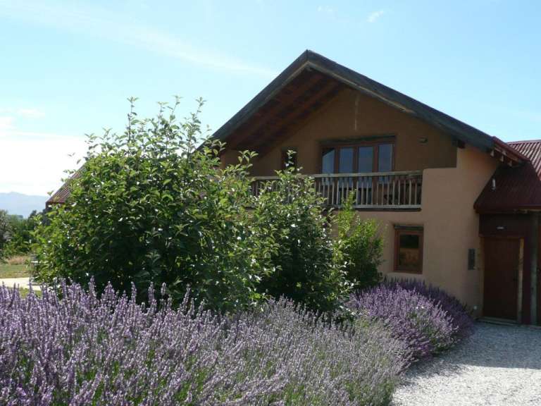 Ein Haus mit einem Balkon und lila Blumen vorne