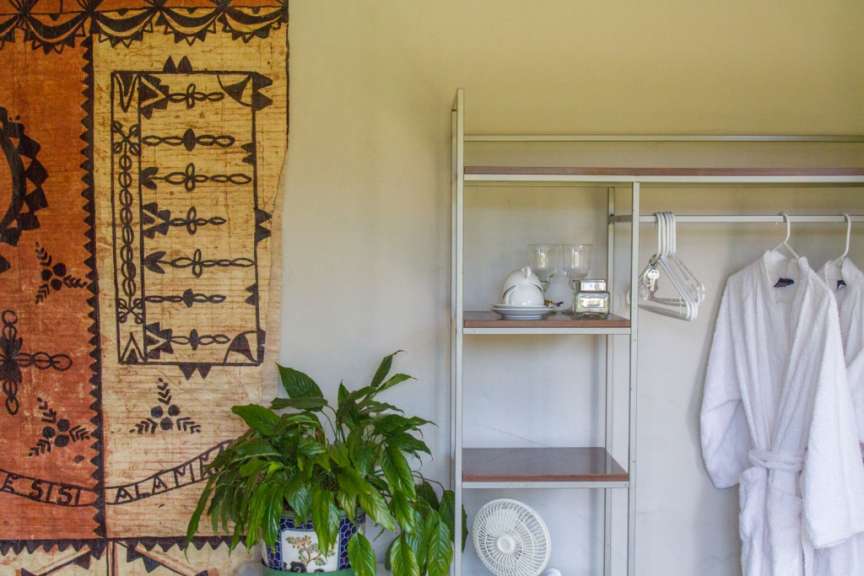 Ein Wandteppich hängt an einer Wand neben einem Regal und einem Ventilator