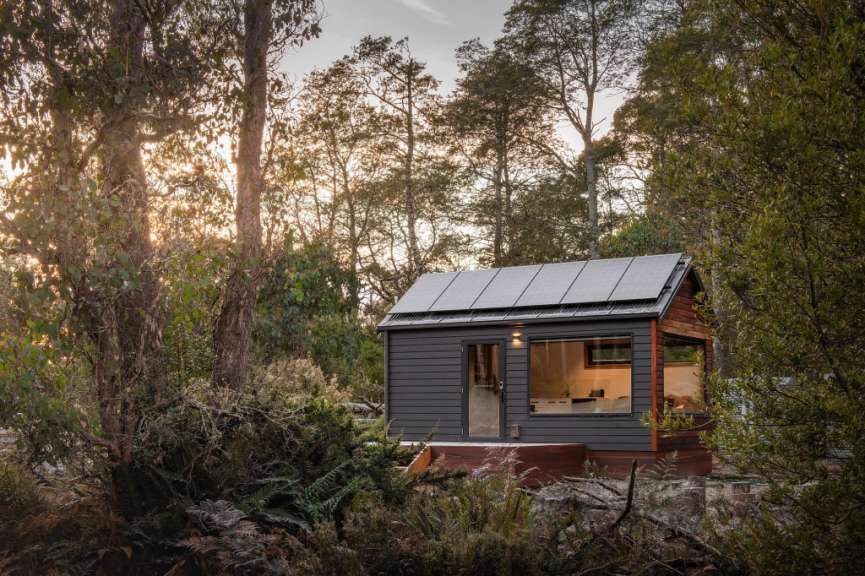 Ein kleines Haus im Wald mit Sonnenkollektoren auf dem Dach
