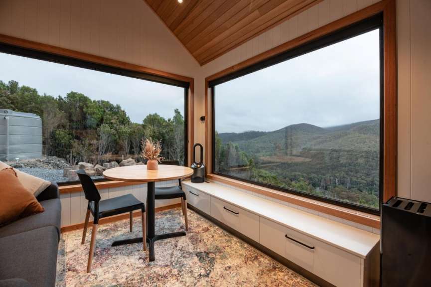 Ein Wohnzimmer mit einem Tisch und Stühlen und einem großen Fenster mit Blick auf die Berge