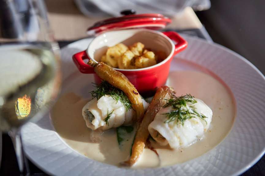 Ein weißer Teller mit einem roten Topf mit Kartoffelpuffern darauf
