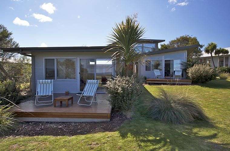 Ein kleines Haus mit einem Deck und Stühlen davor