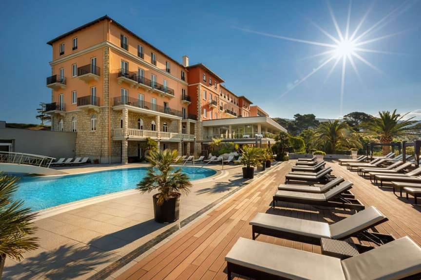 Ein großes Gebäude mit einem Pool und Liegestühlen davor