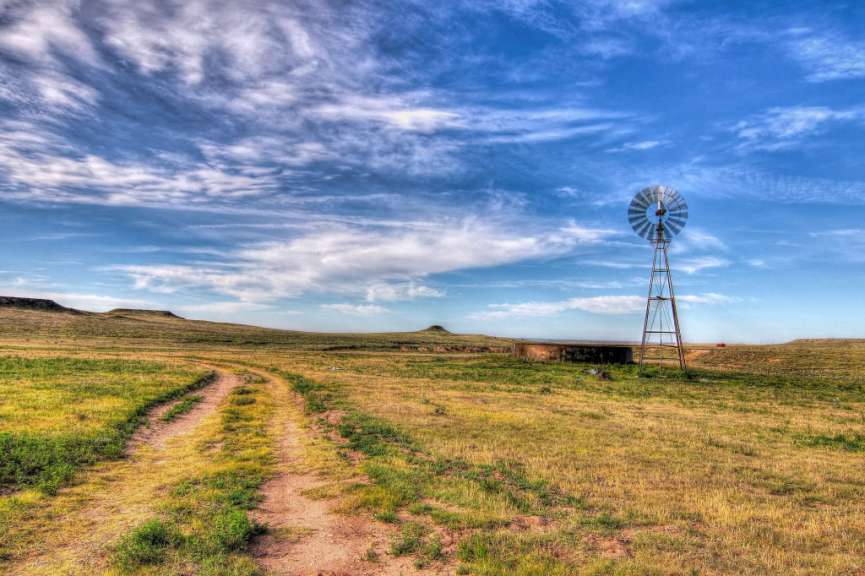 Ein Feldweg mit einer Windmühle im Hintergrund