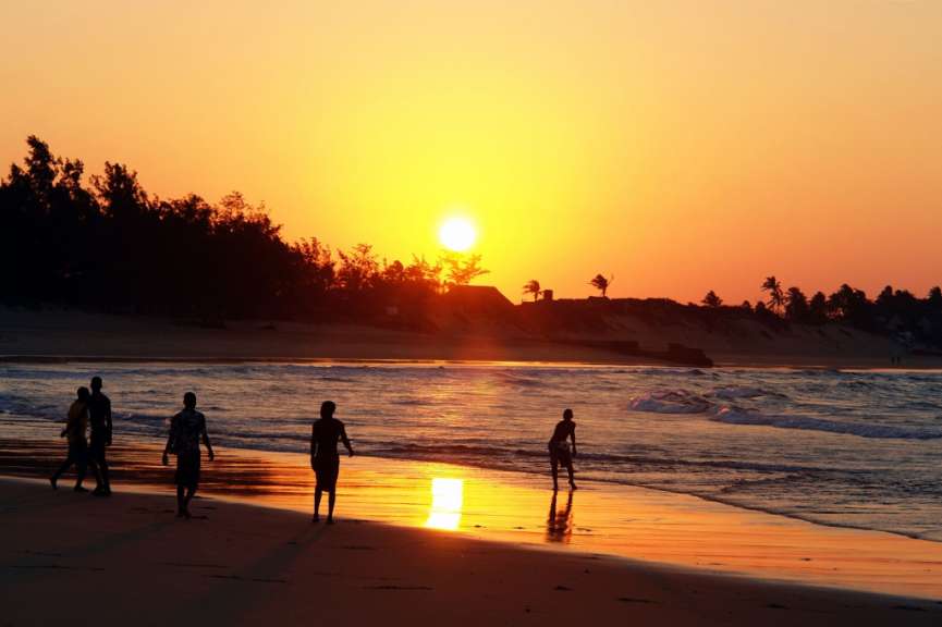 Eine Gruppe von Menschen geht bei Sonnenuntergang am Strand spazieren