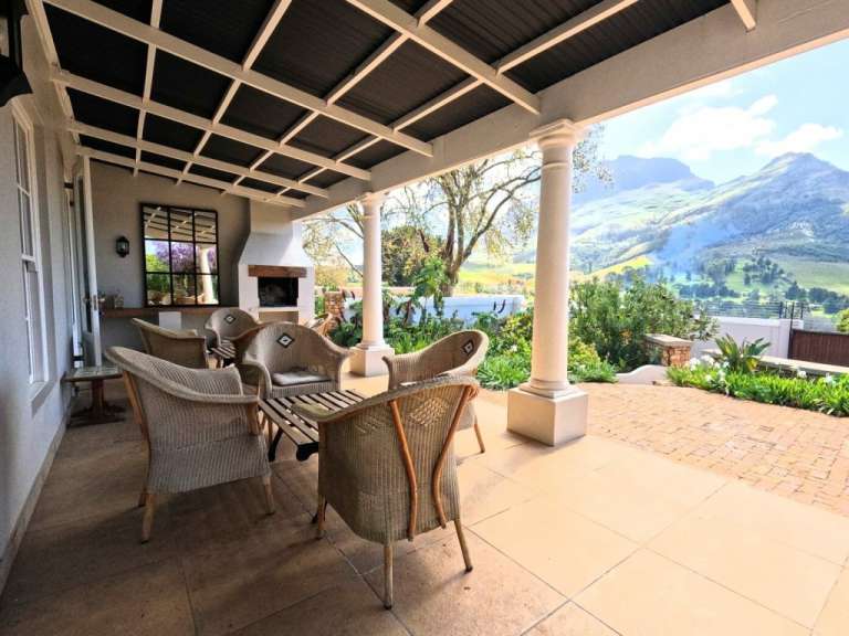 Eine Veranda mit Stühlen und einem Tisch und einem Kamin