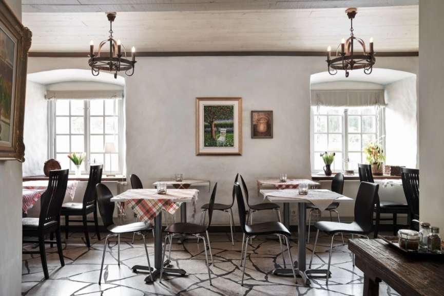 Ein Esszimmer mit Tischen und Stühlen und einem Gemälde an der Wand