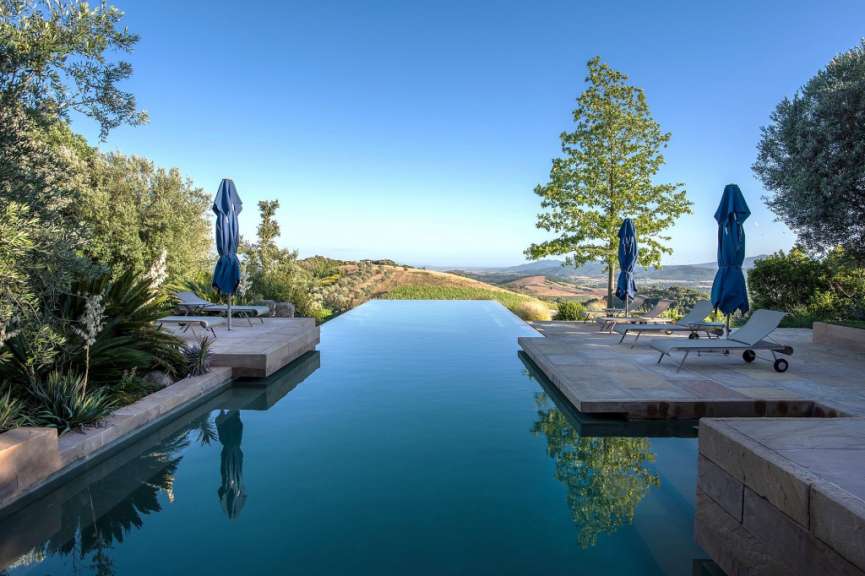 Ein Infinity-Pool mit blauen Sonnenschirmen und Liegestühlen