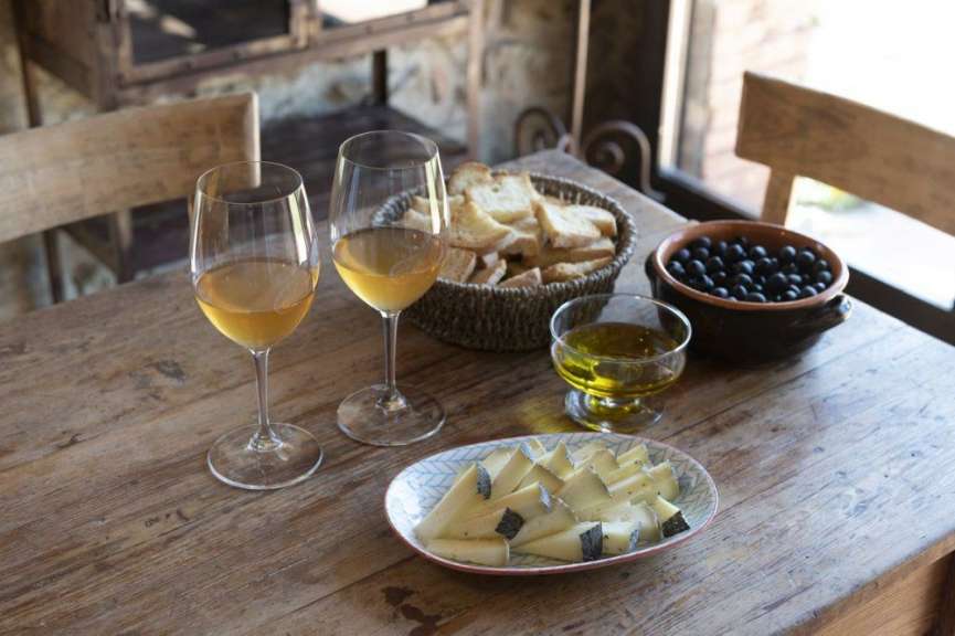 Ein Holztisch mit zwei Gläsern Wein und einem Teller Käse