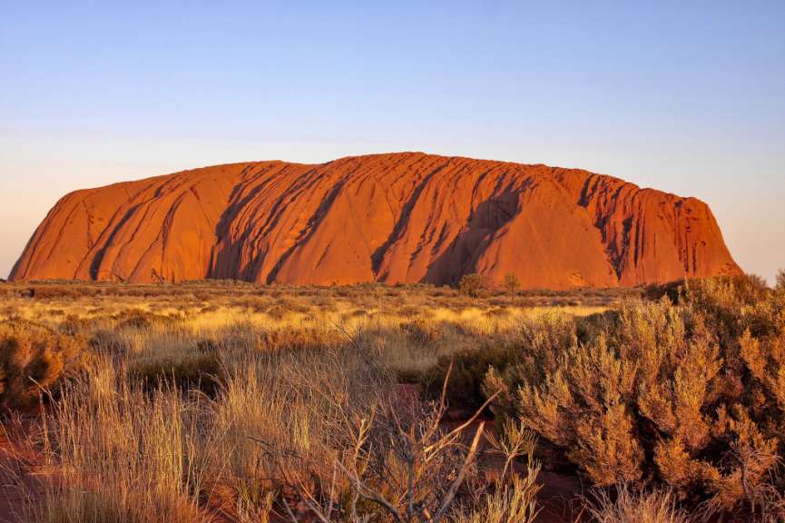 Ein großer roter Felsen in der Mitte einer Wüste